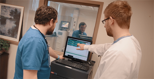 2 nurses reviewing data on computer screen.